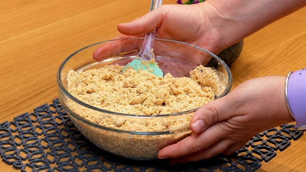 Mixing ground cookies with milk to make the crust, then pressing the crumb mixture evenly into a 24 cm (9.5-inch) springform pan.