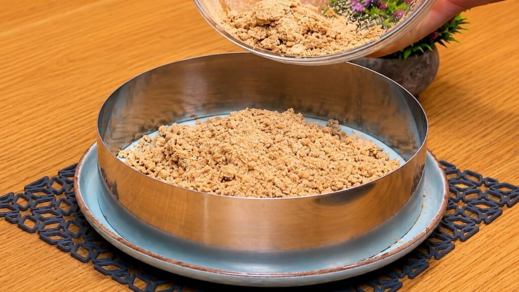 Mixing ground cookies with milk to make the crust, then pressing the crumb mixture evenly into a 24 cm (9.5-inch) springform pan.