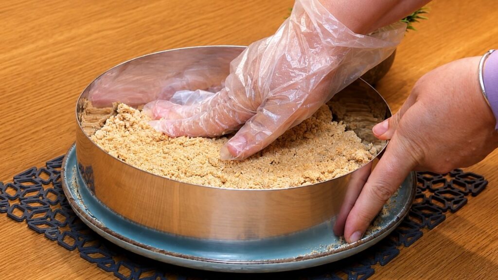 Mixing ground cookies with milk to make the crust, then pressing the crumb mixture evenly into a 24 cm (9.5-inch) springform pan.