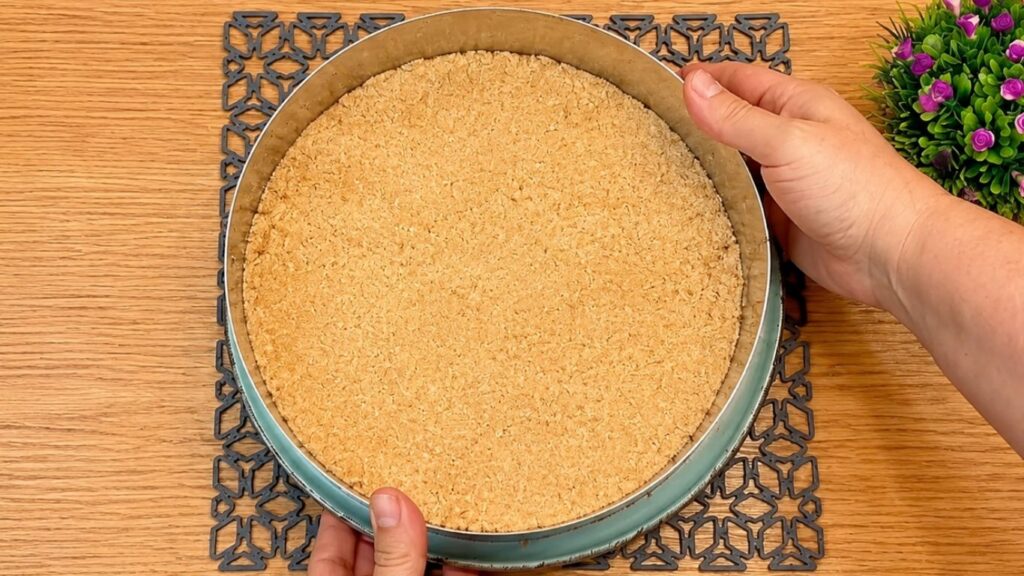 Mixing ground cookies with milk to make the crust, then pressing the crumb mixture evenly into a 24 cm (9.5-inch) springform pan.