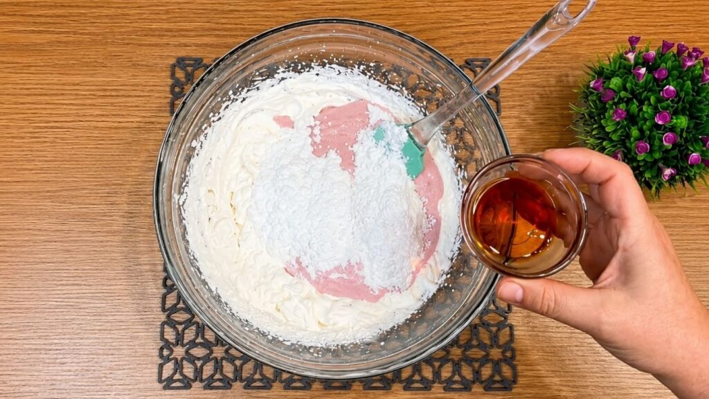 Adding strawberry yogurt, sugar, vanilla extract, and chopped strawberries into the whipped cream, then mixing gently until the filling is smooth and evenly combined.