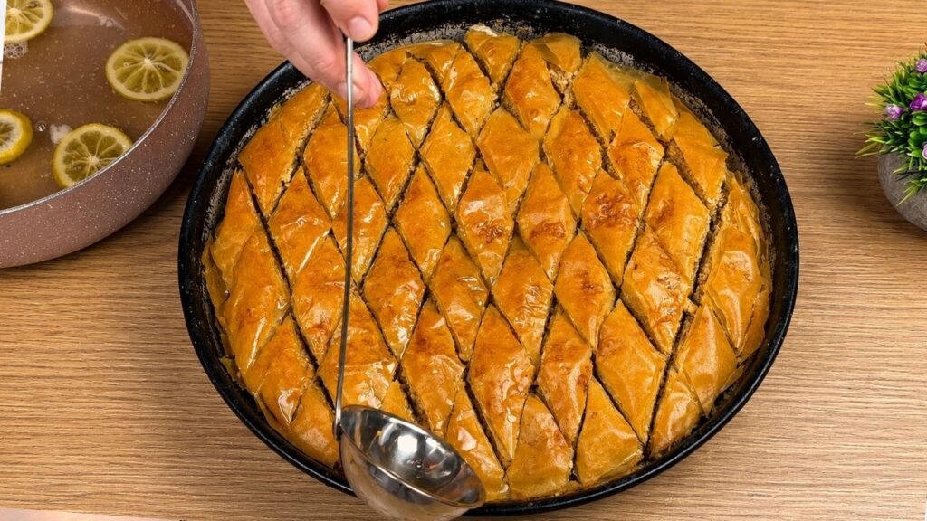 Pouring hot syrup over freshly baked baklava for a crispy and juicy baklava recipe.