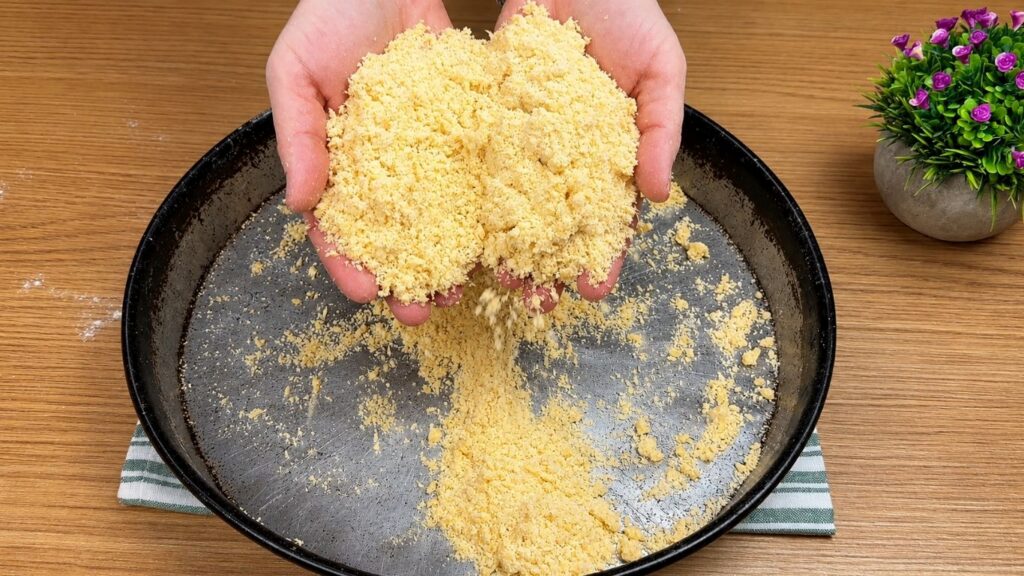 Hands rubbing flour, butter, and egg together to make homemade pastry crumbs for baklava recipe.