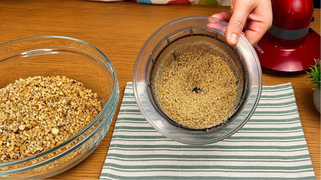 Ground walnuts in a food processor and bowl for homemade baklava recipe filling.
