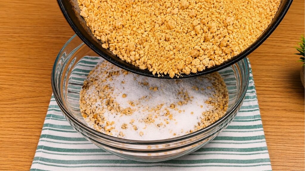Adding homemade pastry crumbs to ground walnuts for baklava recipe filling.