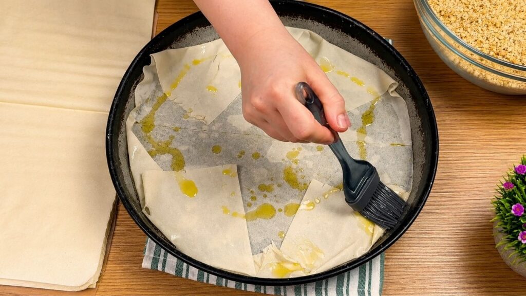 Brushing phyllo dough with melted butter while layering homemade baklava.