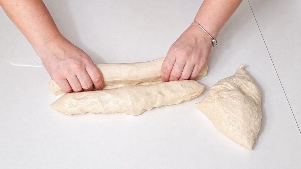 Making Christmas bread wreath dough by hand on a work surface.