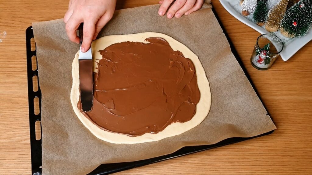 Rolled-out chocolate star bread dough placed on a parchment-lined baking sheet before adding the filling.