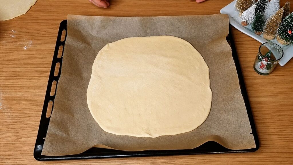 Rolled-out chocolate star bread dough placed on a parchment-lined baking sheet before adding the filling.