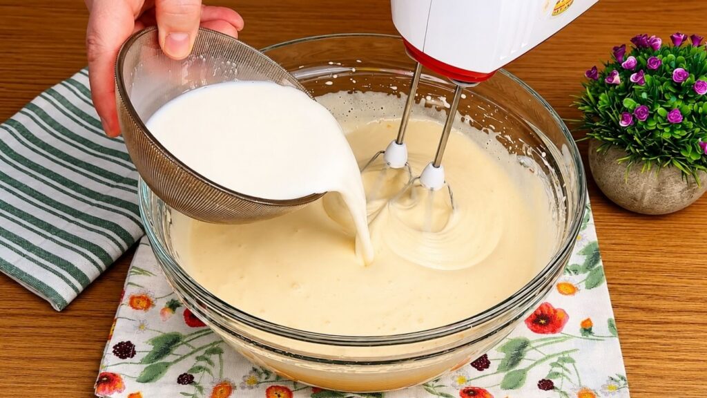Adding oil and milk to whipped eggs and sugar to make a soft and moist chocolate sponge cake batter.