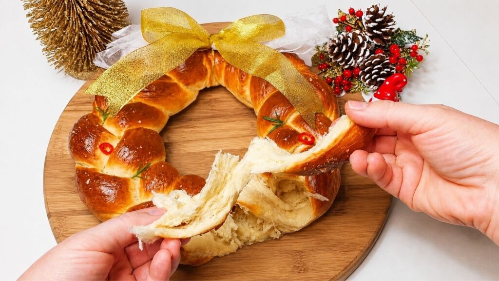 Soft Christmas bread wreath being pulled apart by hand to show the fluffy inside.
