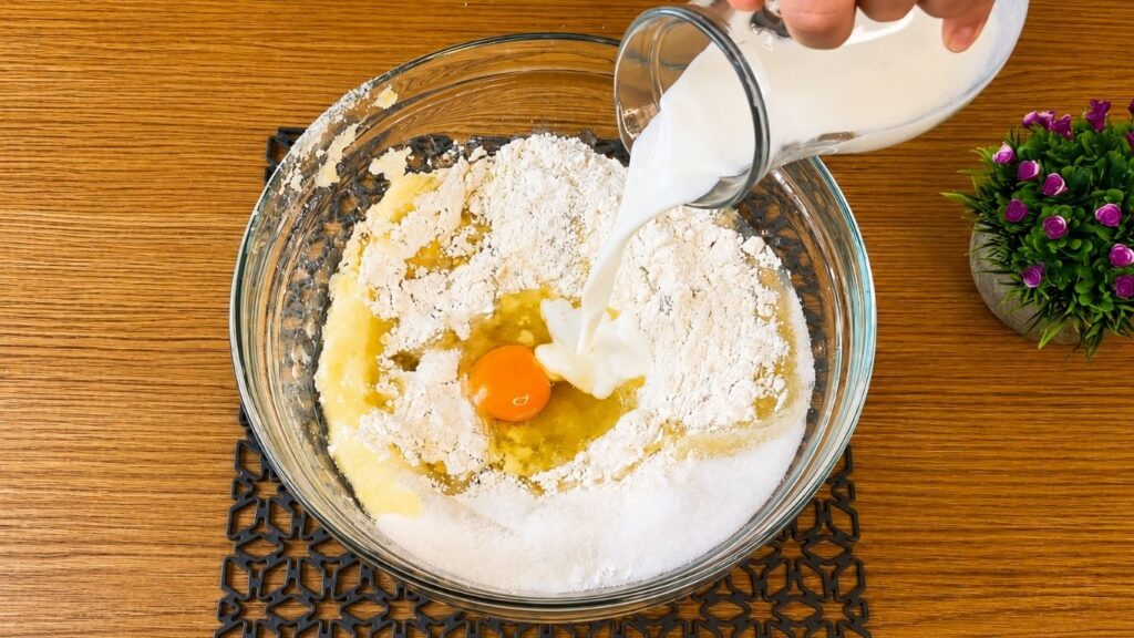 Wet ingredients being added to the dry ingredients for a soft vanilla sponge cake batter.