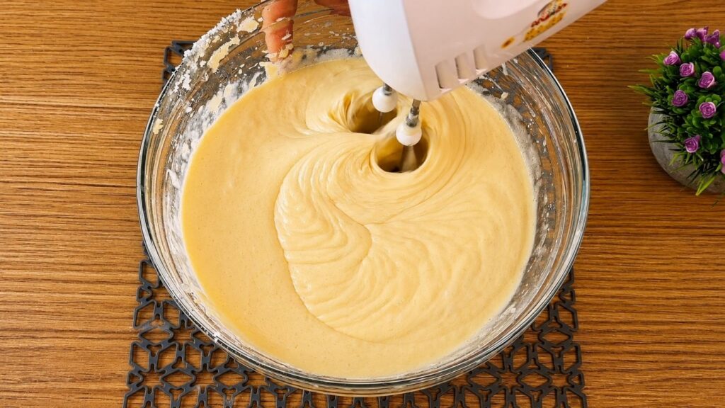 Mixing the vanilla sponge cake ingredients with a hand mixer until the batter comes together.