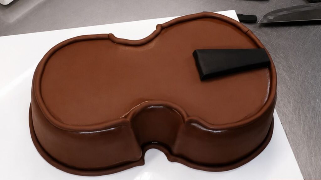 Adding fondant details to the violin body to make the realistic 3D violin cake look more lifelike.