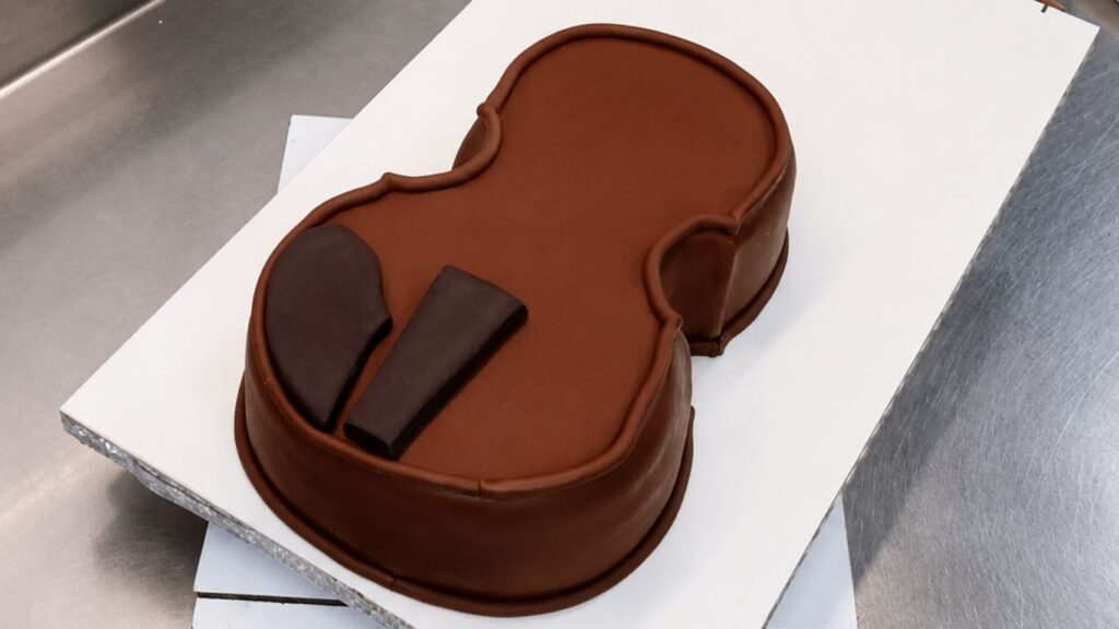 Adding fondant details to the violin body to make the realistic 3D violin cake look more lifelike.