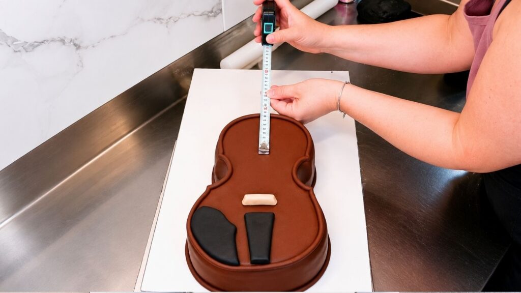 Adding fondant details to the violin body to make the realistic 3D violin cake look more lifelike.