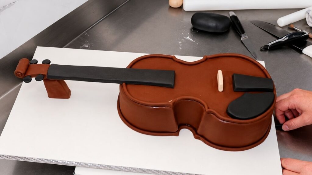 Adding fondant details to the violin body to make the realistic 3D violin cake look more lifelike.
