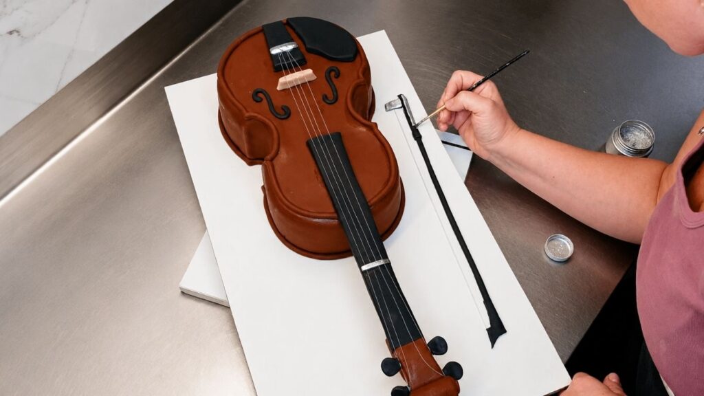 Painting the violin cake details to enhance the realistic 3D design and finished instrument look.