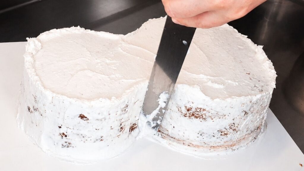 Applying buttercream to the carved chocolate cake base before covering the 3D violin cake with fondant.