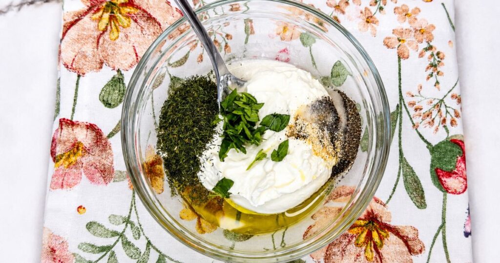 Sour cream, apple cider vinegar, olive oil, dill, garlic powder, salt, and black pepper in a bowl for the creamy dressing.