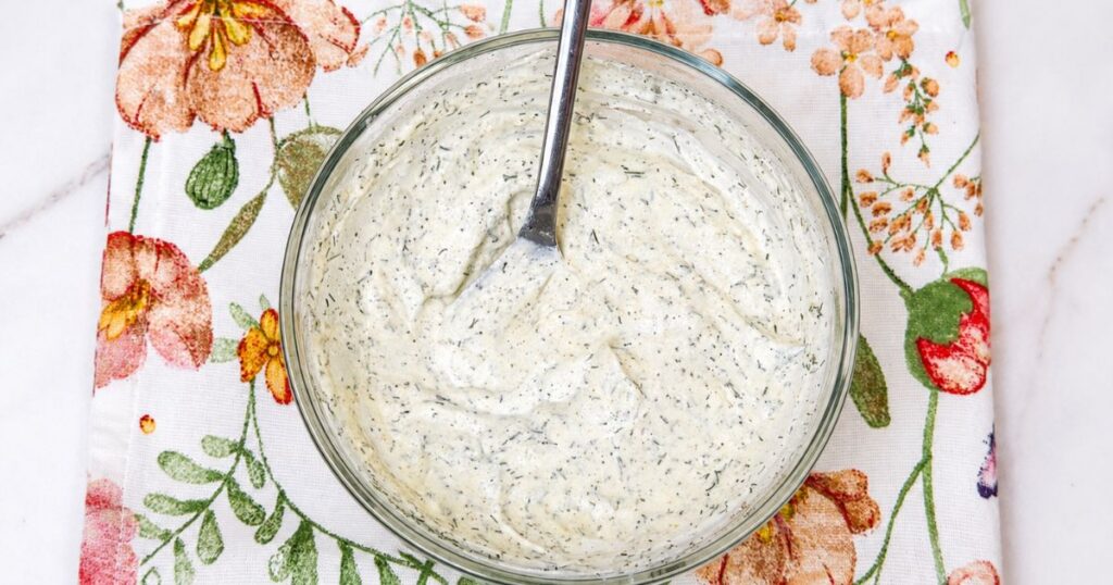 Creamy sour cream dressing mixed and ready to pour over the sliced cucumber and red onion.