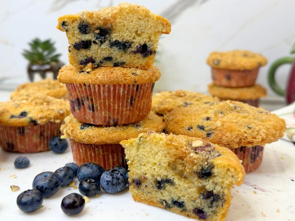 Moist blueberry muffins with a cut muffin showing the soft blueberry-filled center