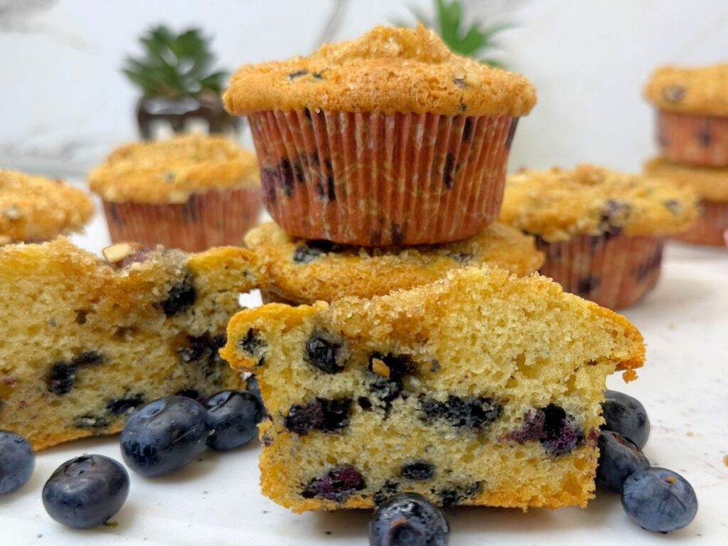 Moist blueberry muffins with a cut muffin showing the soft blueberry-filled center