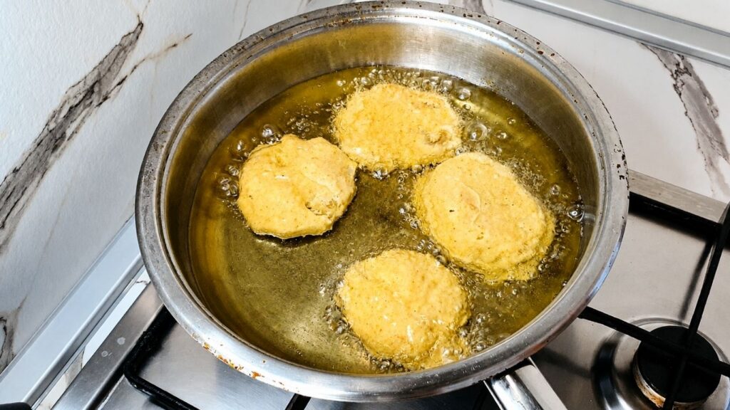 Breaded eggplant slices frying in hot oil until golden brown.