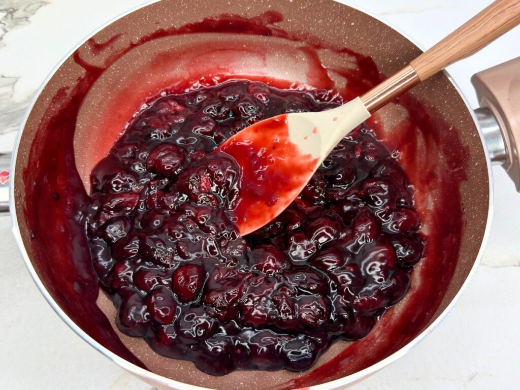 Thickened cherry filling cooked in a saucepan for homemade cherry crumb bars.