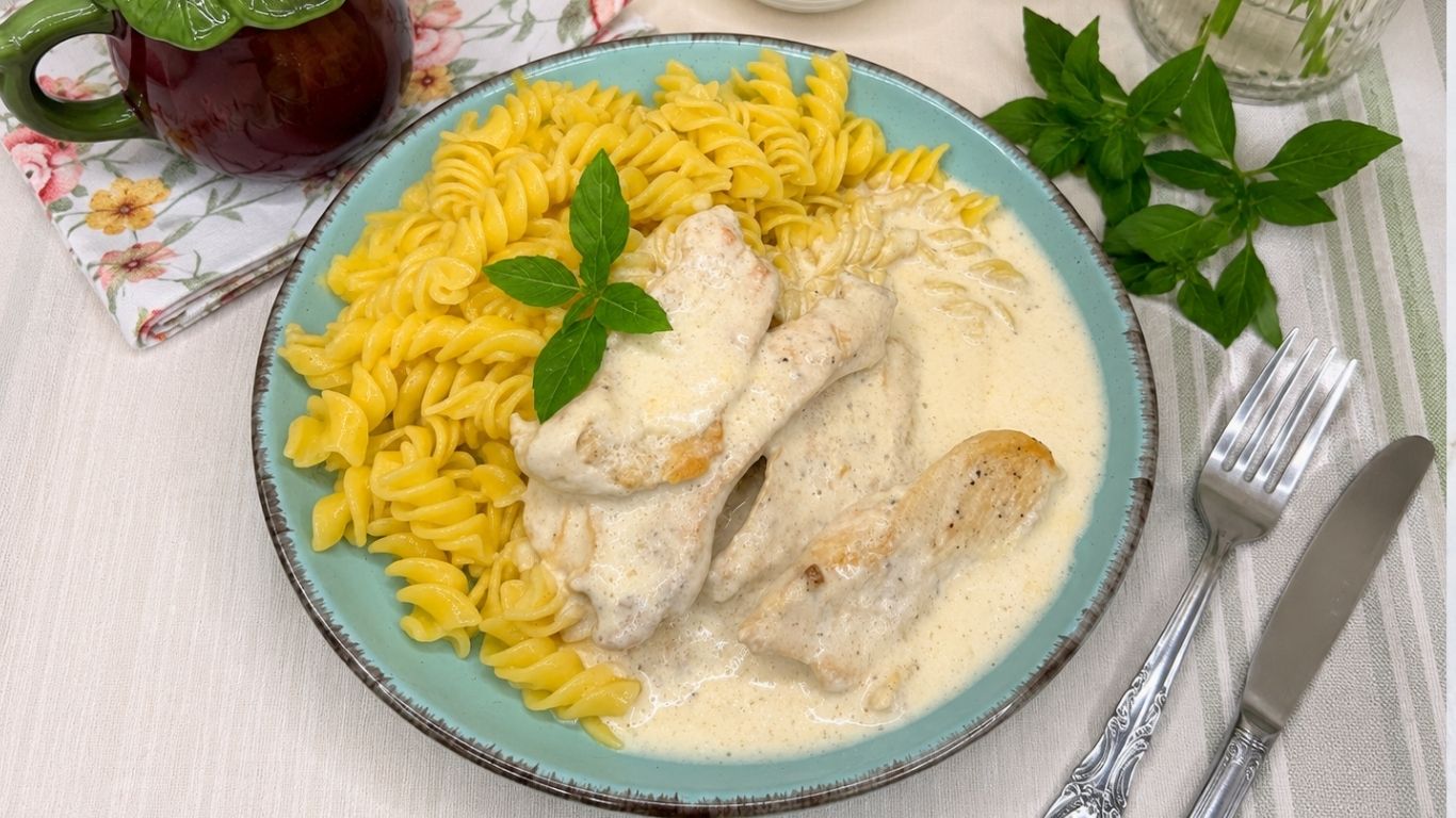 Creamy chicken pasta with tender chicken fillets in a rich white sauce, served with rotini pasta.