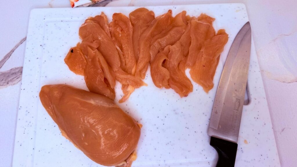 Thinly sliced chicken breasts prepared for creamy chicken pasta.