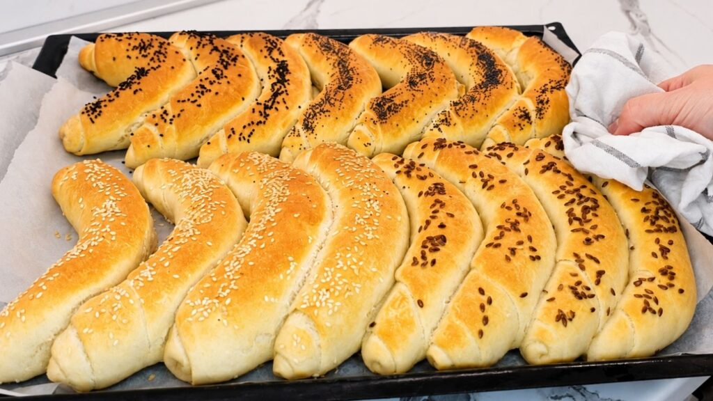 Golden brown, freshly baked crescent rolls arranged in a baking pan, hot out of the oven.