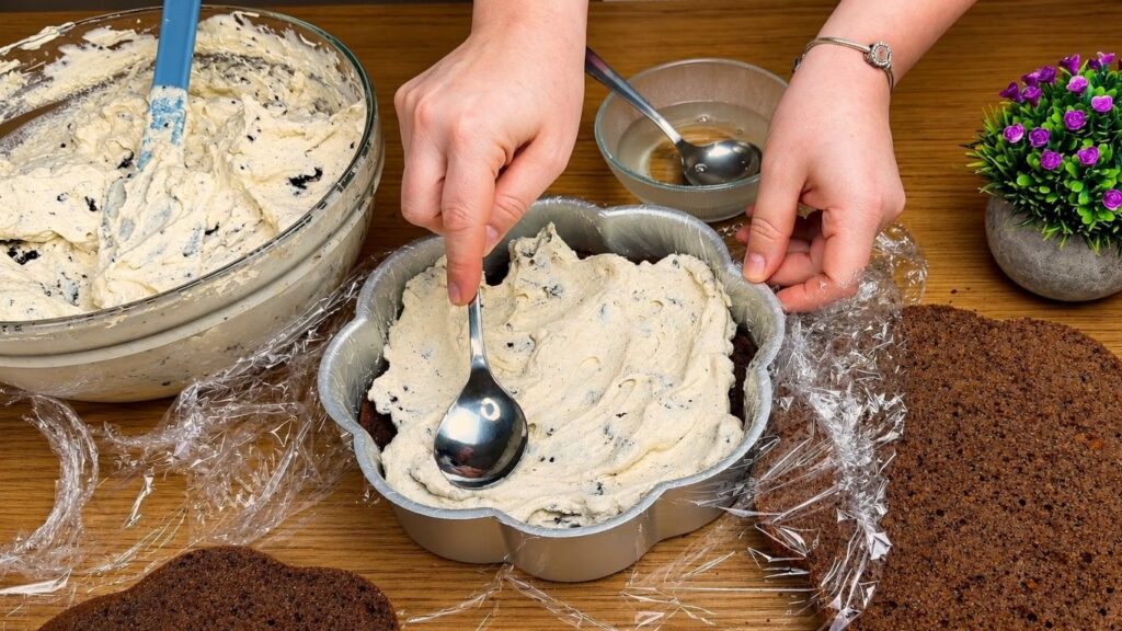 Adding Oreo cream filling to a chocolate cake layer.