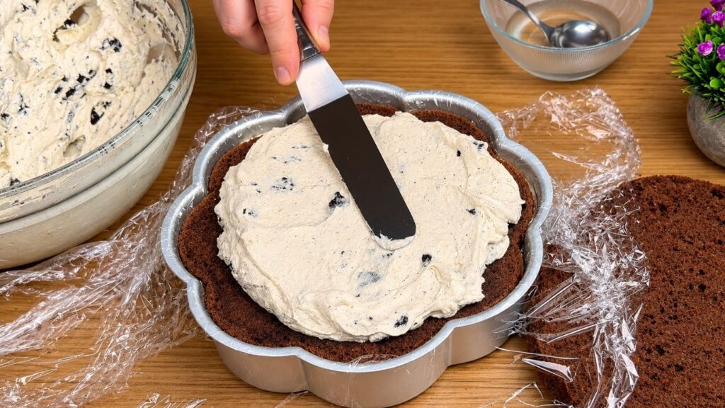 Adding Oreo cream filling to a chocolate cake layer.