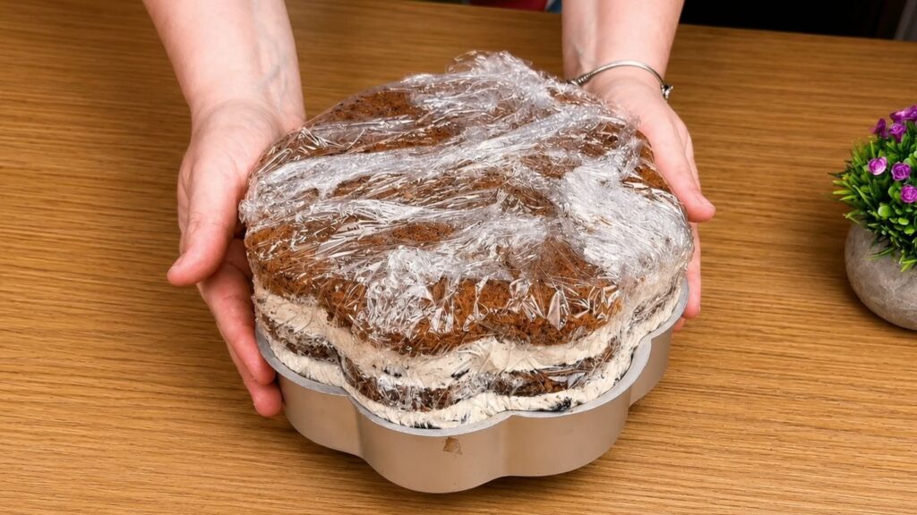 Filled cake wrapped in plastic wrap before chilling.