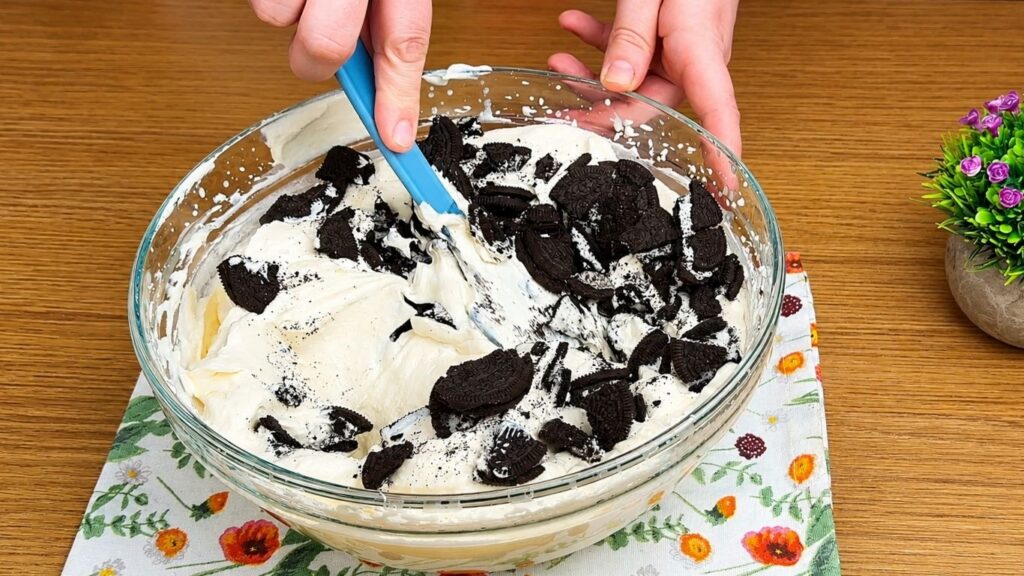 Adding crushed Oreo cookies to the cream filling.