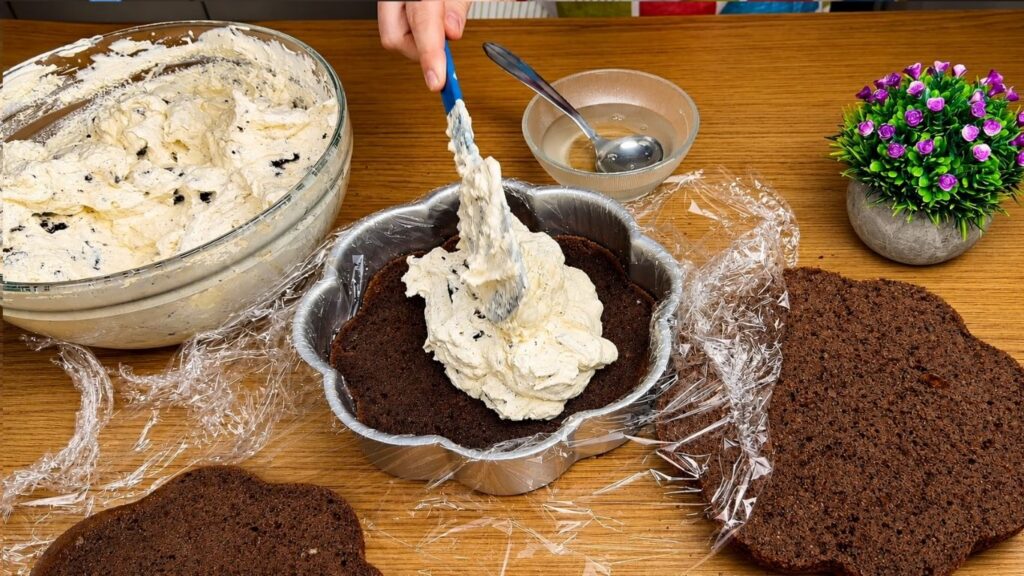 Adding Oreo cream filling to a chocolate cake layer.