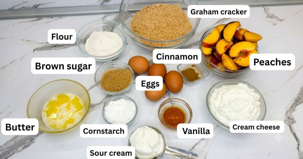 Ingredients for Peach Cobbler Cheesecake, including cream cheese, peaches, graham crackers, butter, eggs, sour cream, sugar, and crumble ingredients.