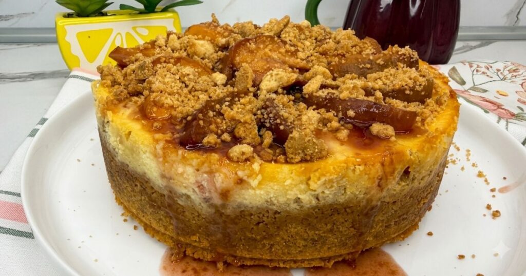Finished Peach Cobbler Cheesecake displayed on a cake board, ready to slice and serve.
