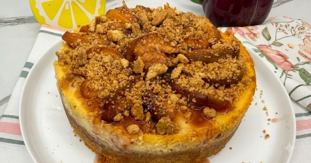 Finished Peach Cobbler Cheesecake displayed on a cake board, ready to slice and serve.