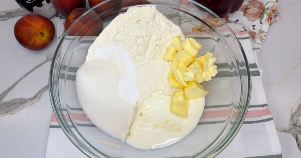 Cobbler topping mixture with flour, sugar, cold butter, buttermilk, baking soda, and salt in a mixing bowl.
