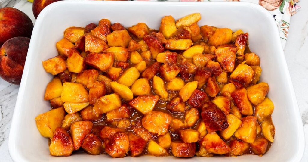 Peach filling spread evenly in a baking dish before adding the cobbler topping.