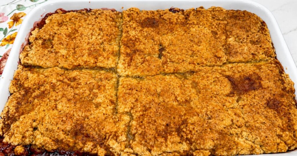 Freshly baked Peach Cobbler with a golden topping and bubbling peach filling in a baking dish.