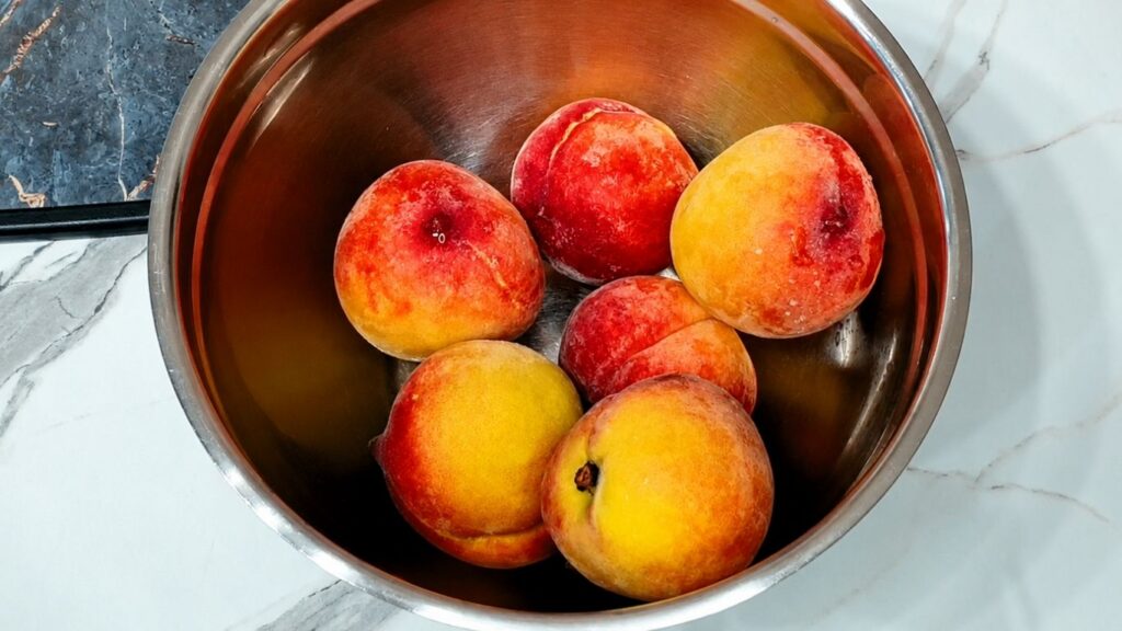 Fresh sliced peaches in a bowl with brown sugar, prepared for homemade peach upside down cake