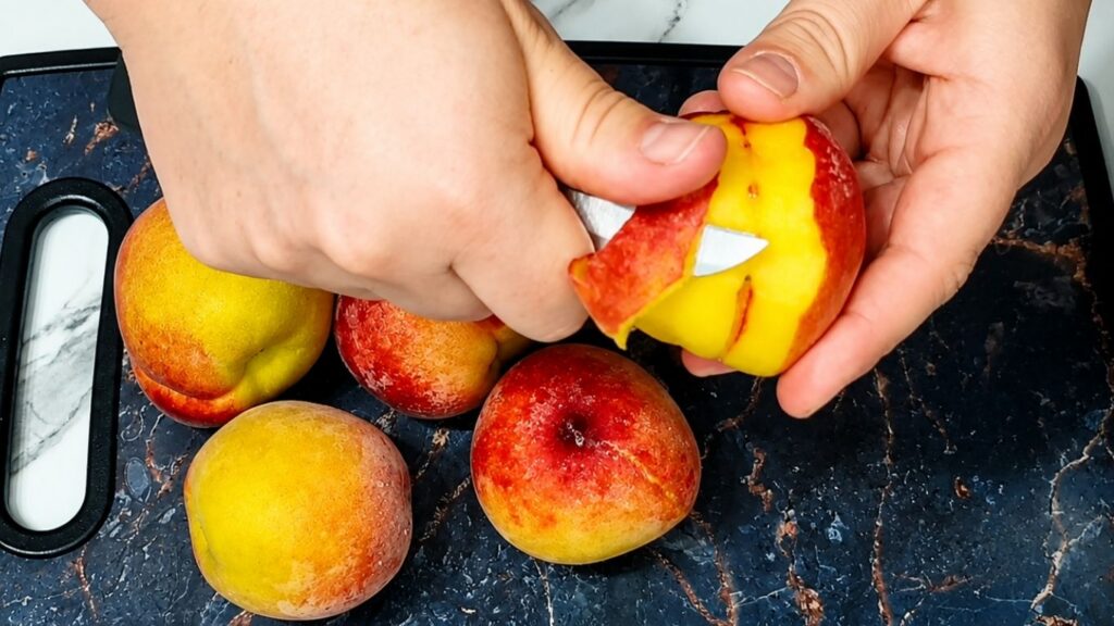 Peeling fresh peaches before slicing them for an easy peach upside down cake recipe
