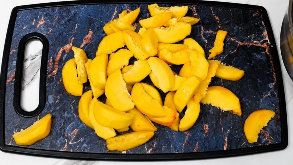 Fresh peaches sliced on a cutting board before arranging them in a pan for peach upside down cake