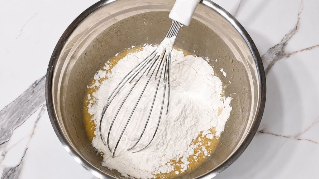 Eggs, milk, oil, and brown sugar in a bowl for making peach upside down cake batter