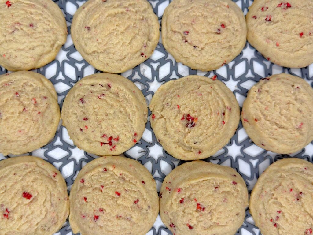 Overhead view of soft raspberry sugar cookies sprinkled with crushed dried raspberries on a white surface.