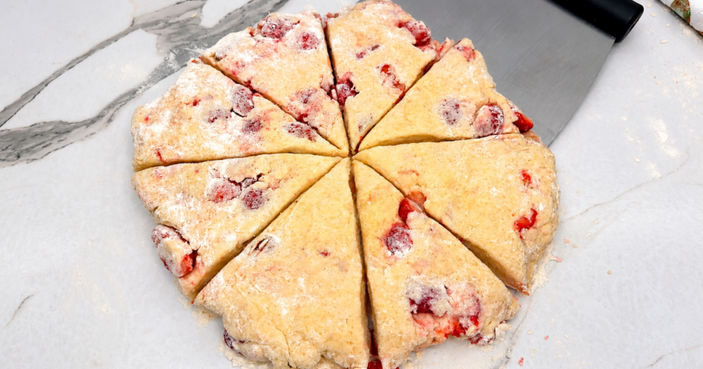 Strawberry scone dough divided into 8 equal pieces on a floured work surface.