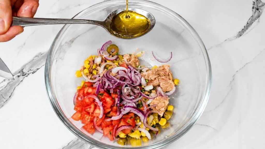 Chopped vegetables in a bowl being seasoned with spices and olive oil